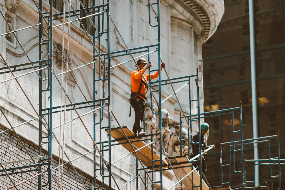 Trabalhador sobre plataforma de andaime de fachada com guarda-corpo