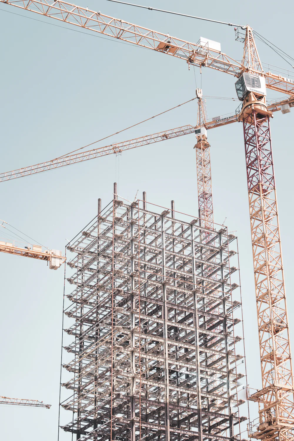 Estrutura metálica de um edifício em montagem, com gruas ao fundo